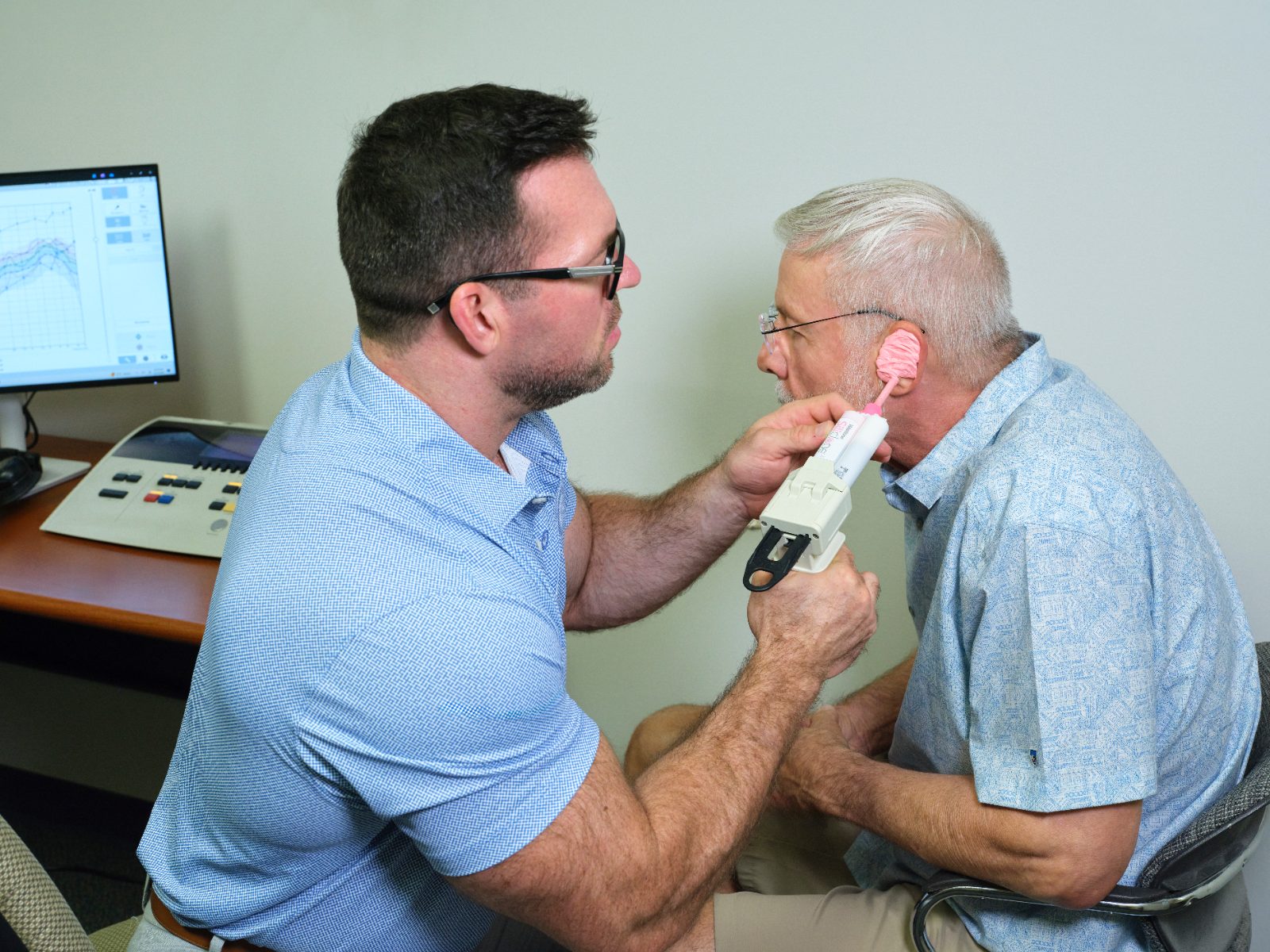 Andy Schirmer taking a silicone ear impression from a patient in the office